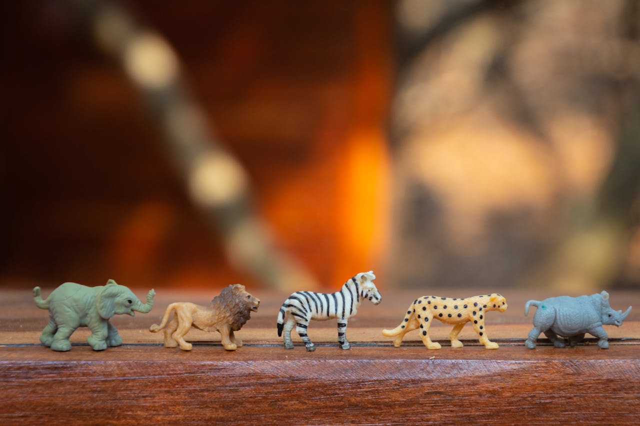 Home Miniature toy animals in a row on wood, displaying various wild species.